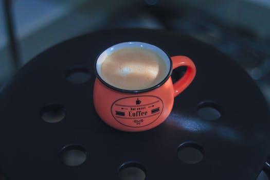 Relaxing cappuccino in a vintage red mug on a dark table offers a cozy coffee experience.