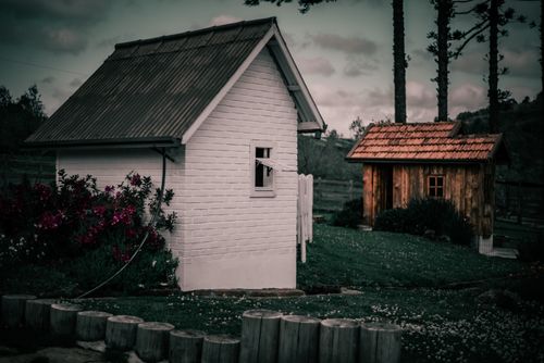 Free Charming countryside view featuring rustic houses surrounded by lush greenery and wooden fences. Stock Photo