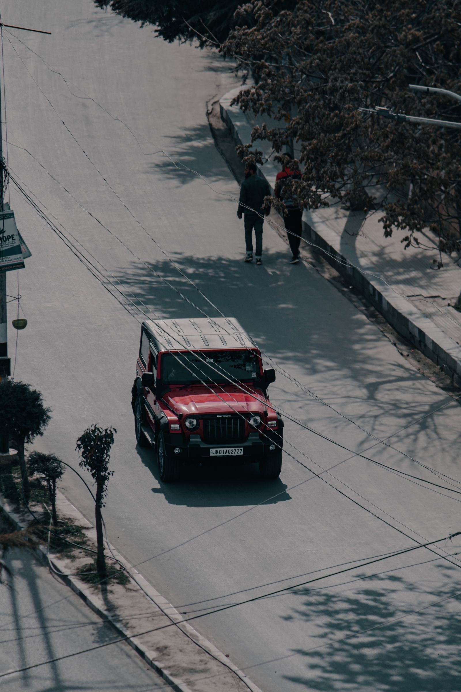 A vehicle driving down a tree-lined Indian road