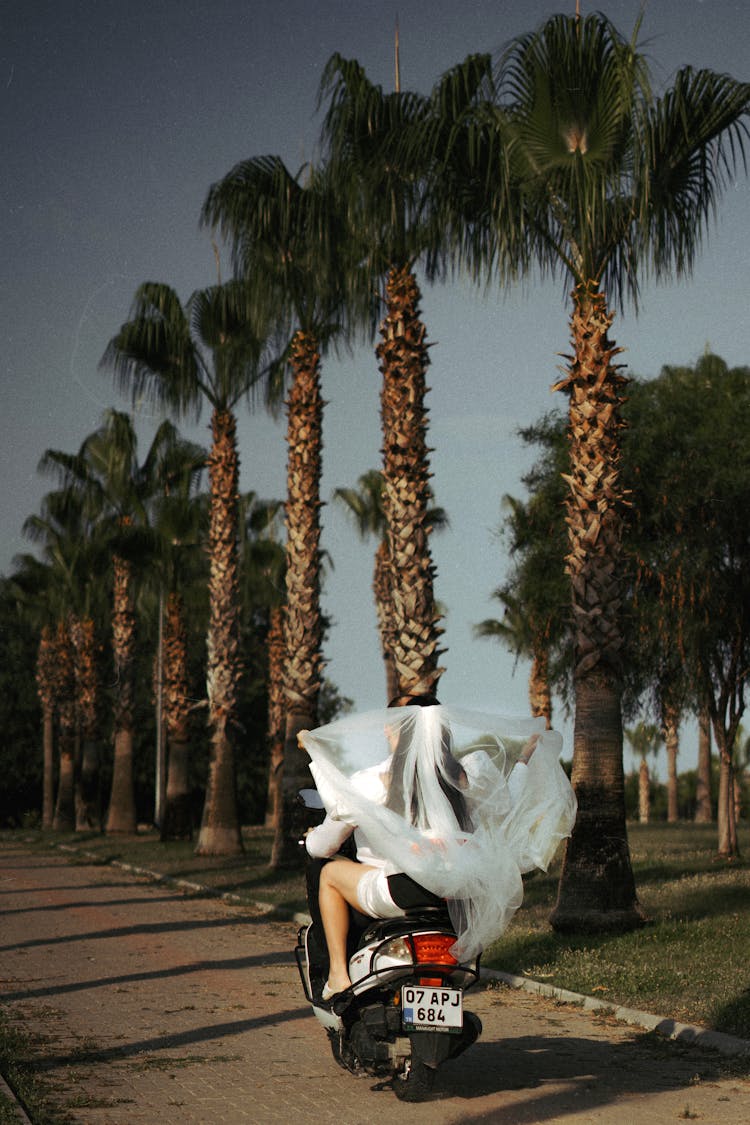 Bride And Groom Driving Away On A Scooter 