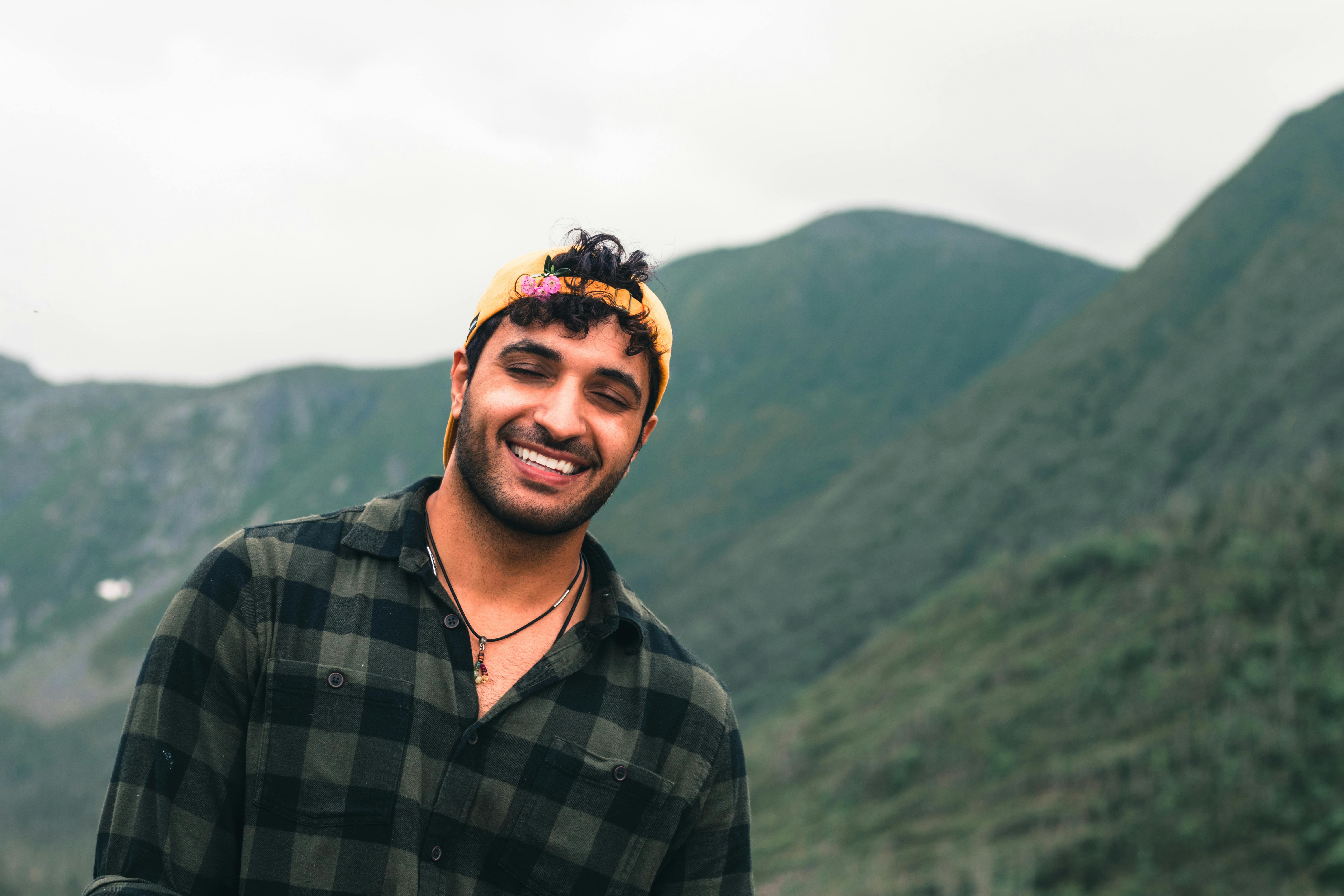 Happy man wearing cap and plaid shirt, smiling in front of Quebec