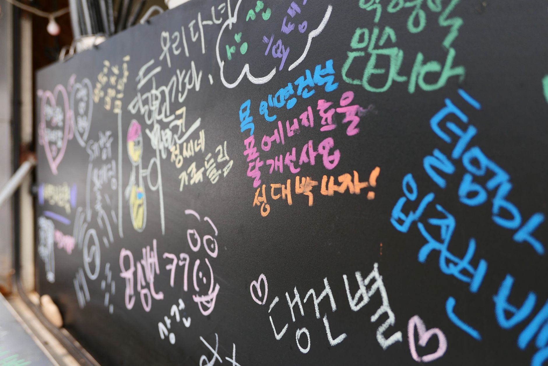 Vibrant chalk messages and drawings on a blackboard, showcasing expressive handwriting.