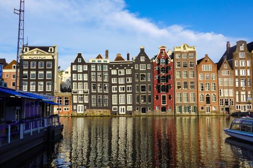 Free Charming view of traditional Dutch canal houses reflected in Amsterdam's clear waters. Stock Photo