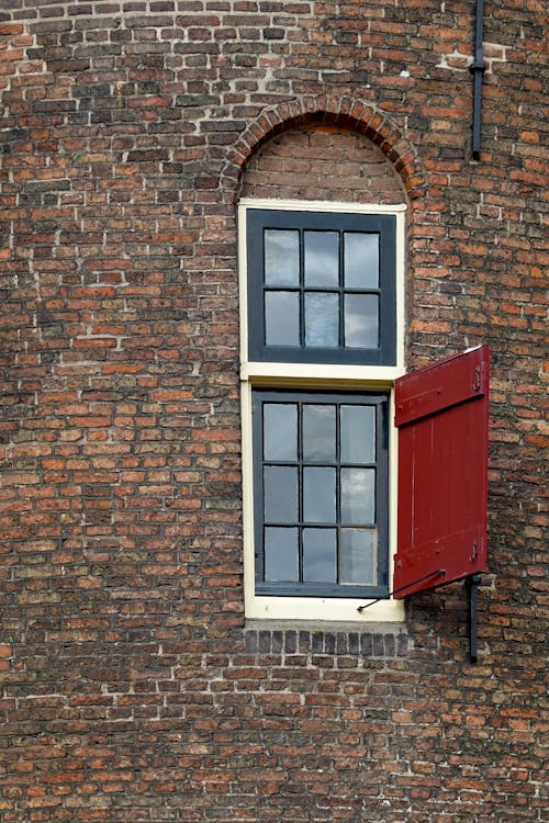 Close-up of a Window with a Red Wooden Shutter in an Old Brick Building 