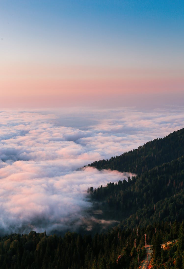 Top View Of Mountains Peak Above The Clouds At Sunset 