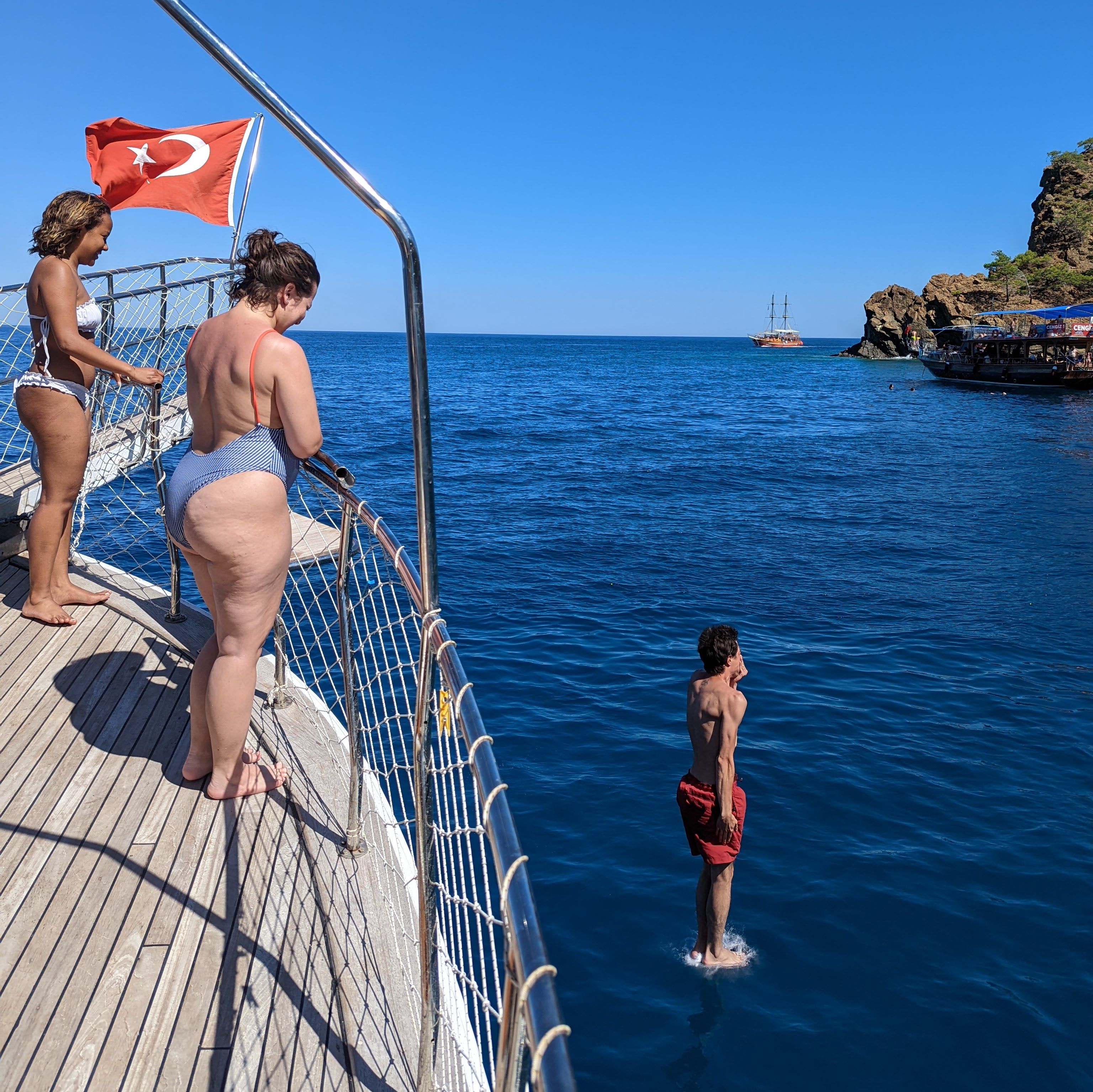 Vacationers diving off a boat in Kemer, Turkey, enjoying the clear blue sea.