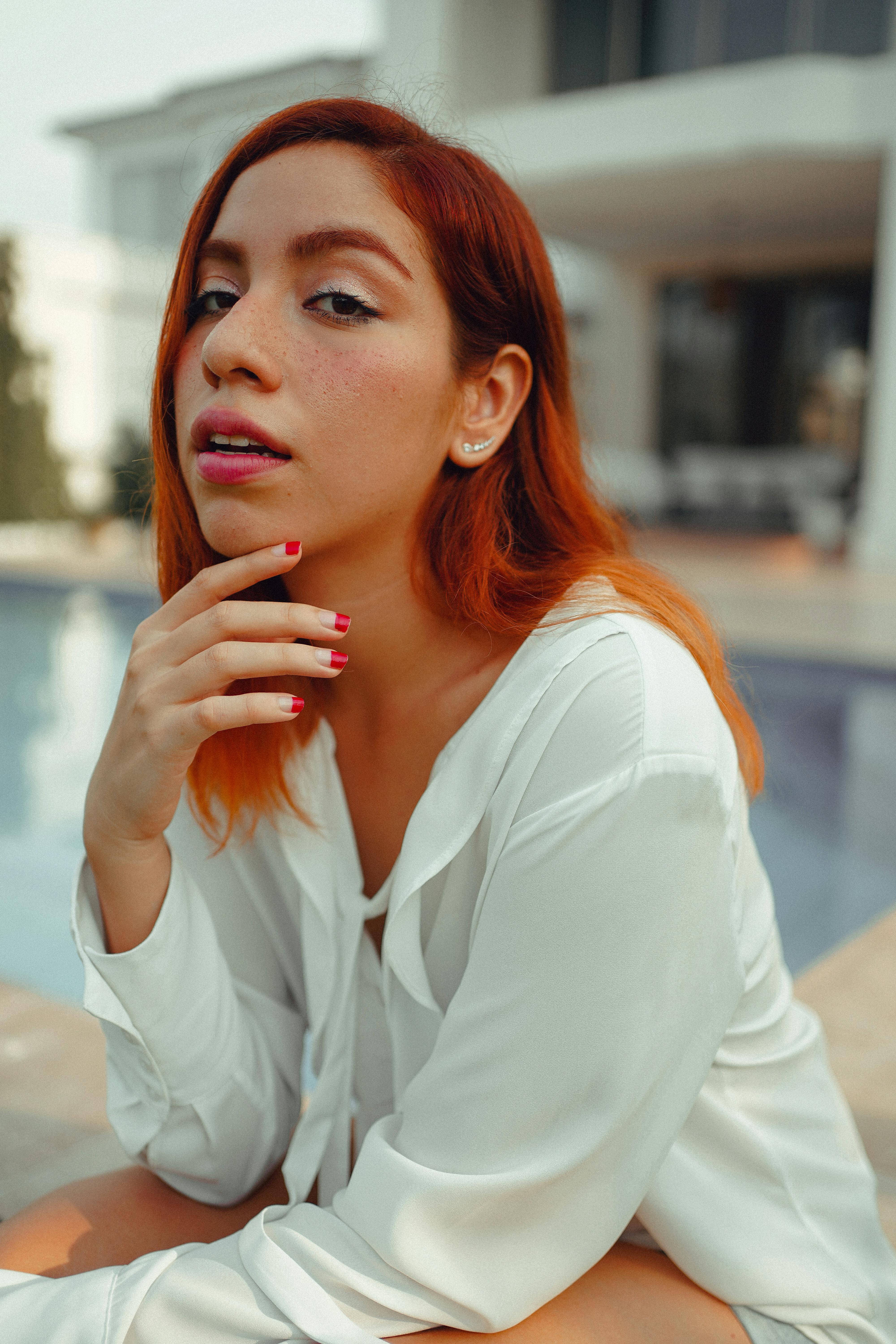 close up shot of a redhead girl in white long sleeves