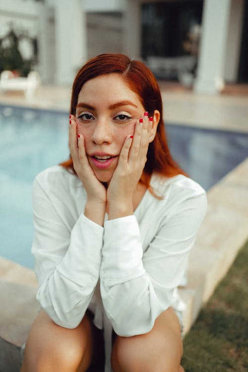 Woman in White Long Sleeve Shirt Sitting on Poolside