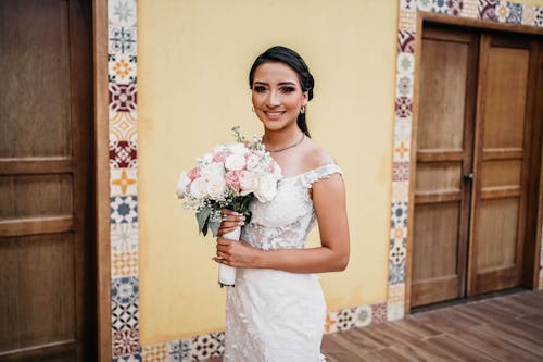 Woman in White Wedding Dress Holding Bouquet of Flowers 