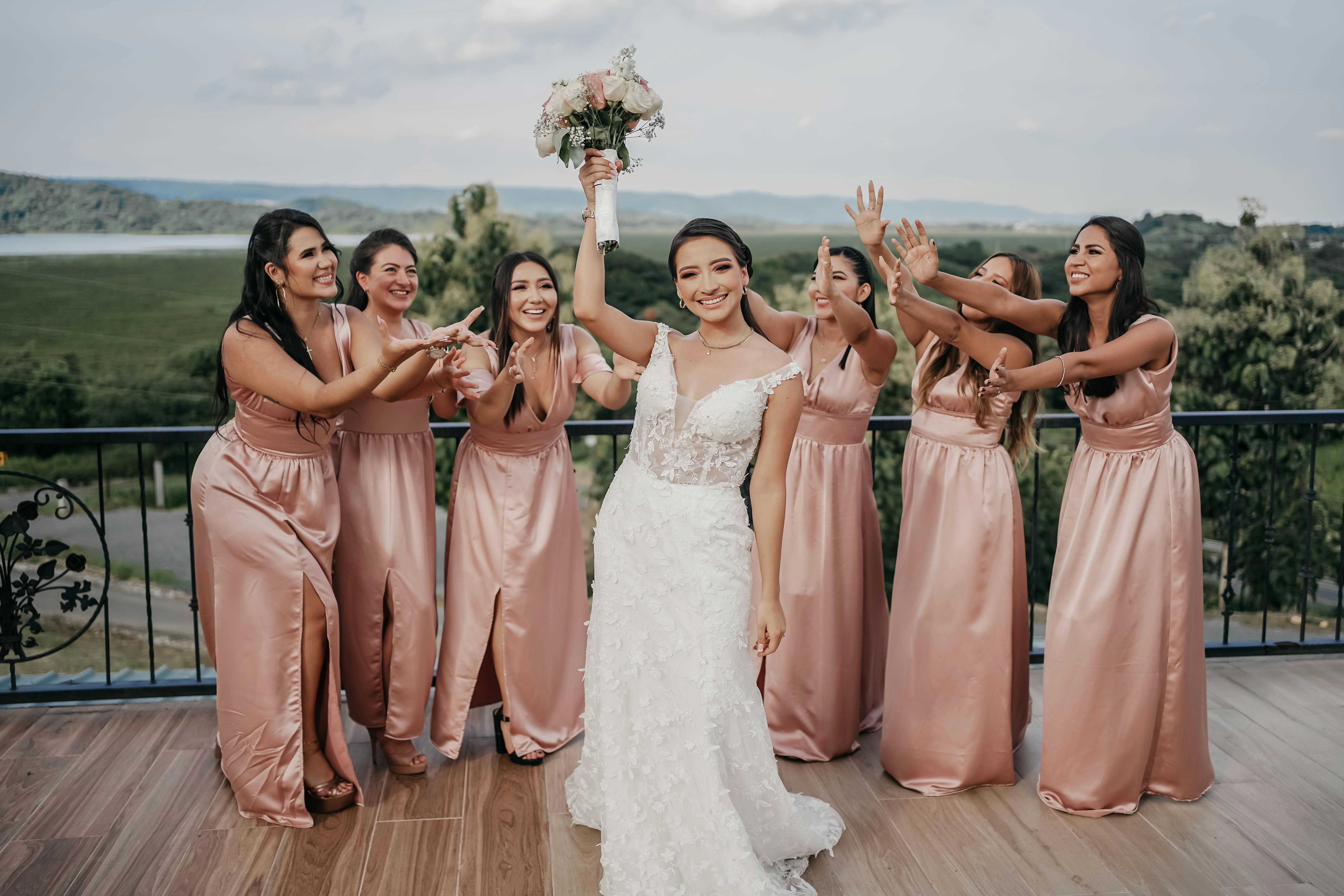 Bride holding bouquet with excited bridesmaids outdoors in Ecuador.