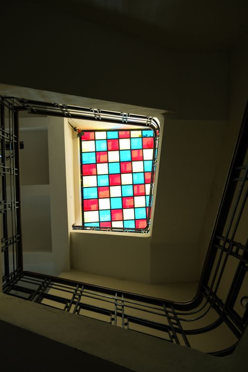Free A low angle view of a staircase featuring a vibrant stained glass ceiling, adding color to the interior. Stock Photo