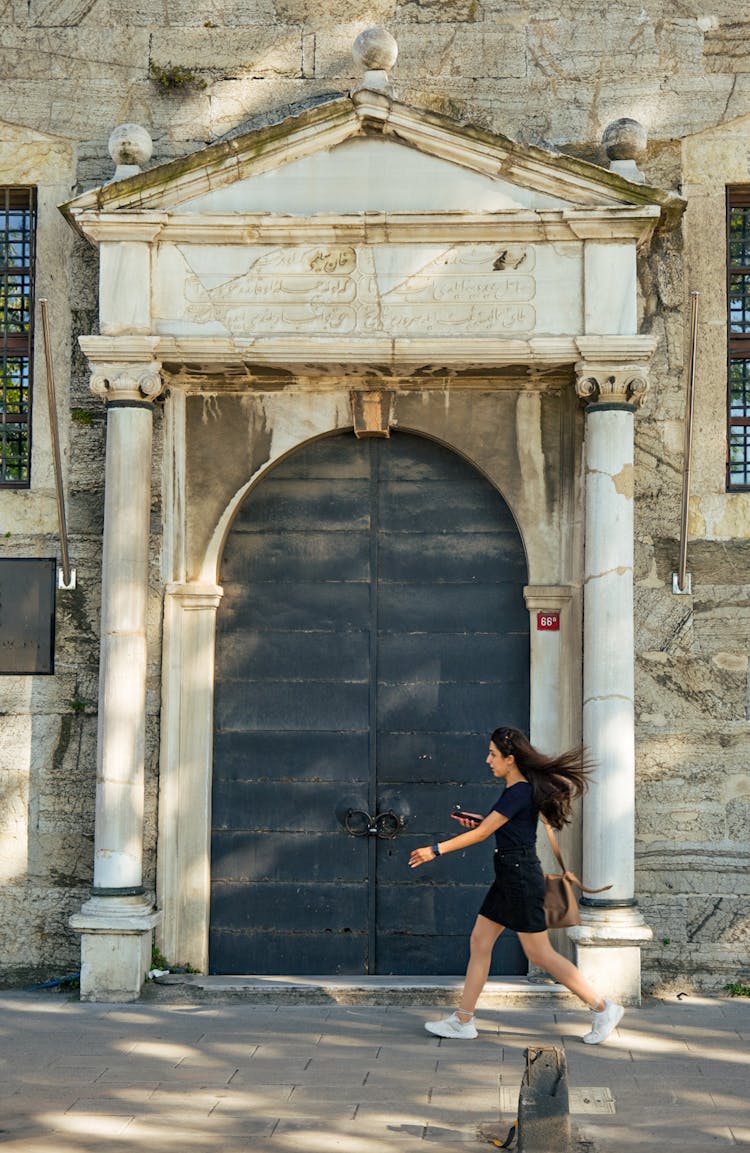 Woman Walking Near Old Building Door