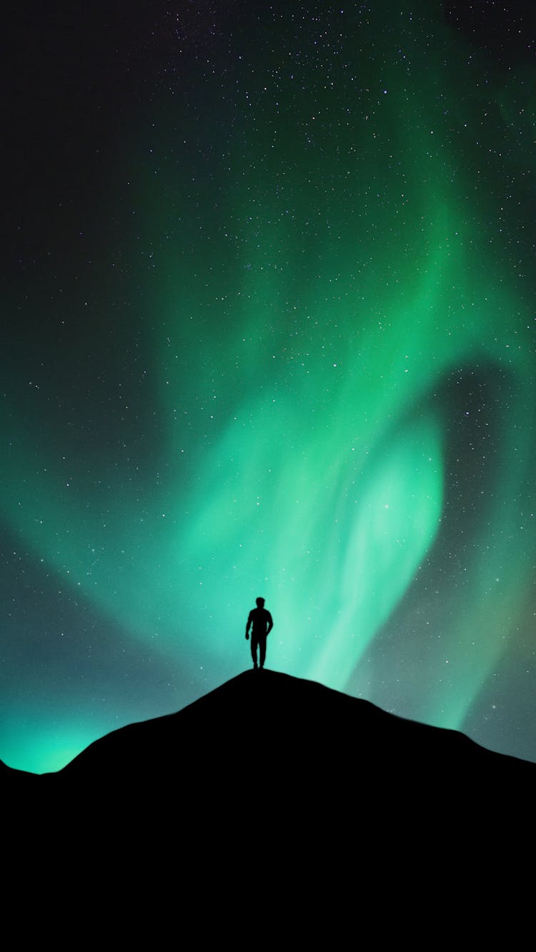 Aurora Borealis Silhouette Of Man Standing On Hill