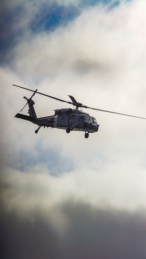 Free A military helicopter navigating through dense clouds in a dramatic sky. Stock Photo