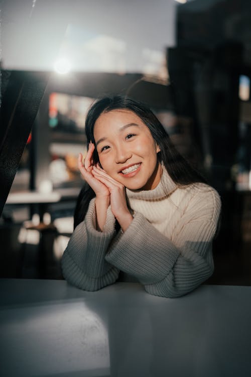 Beautiful Woman Sitting Behind a Table and Smiling 