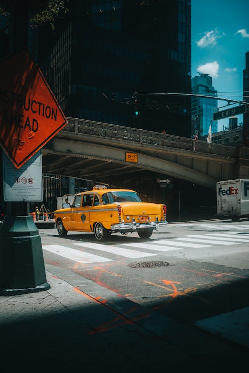 Yellow Taxi Driving Under a Concrete Bridge