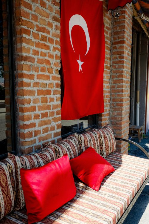 Free Turkish flag hanging by a brick wall over a patterned sofa with vibrant red cushions. Stock Photo