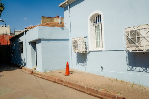 Photo of a Blue Building with Windows and a Traffic Cone on a Pavement