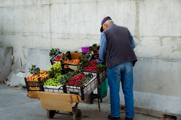 Elderly Man Selling Fresh Fruit On A Market Stall 