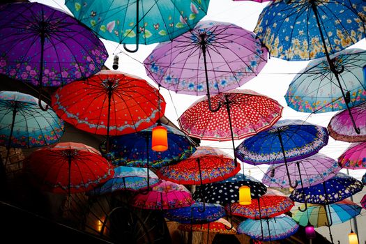 Vibrant display of hanging umbrellas creating colorful street art installation outdoors.