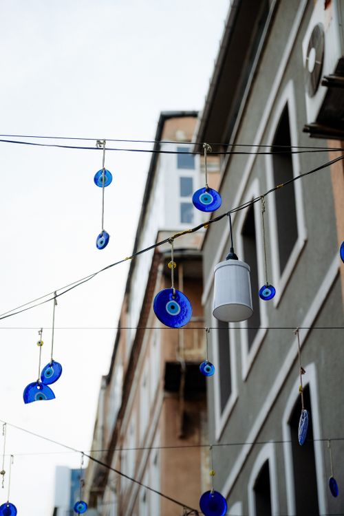 Free Hanging blue evil eye charms in a vibrant urban setting provide cultural charm. Stock Photo