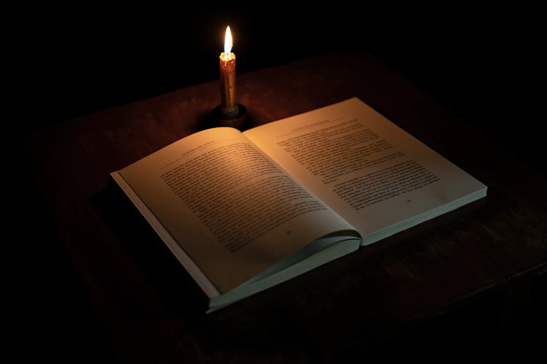 A lit candle next to an open book on a wooden surface, evoking the slow contemplative rhythm of spiritual direction.