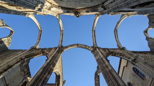 Free Low-angle view of Carmo Convent ruins in Lisbon against a clear blue sky. Stock Photo