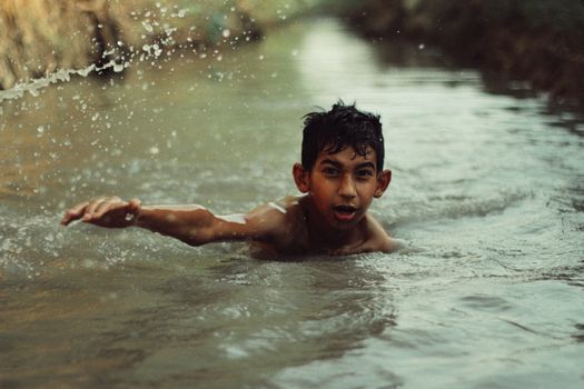 A young boy enjoying a refreshing swim in a tranquil natural stream.