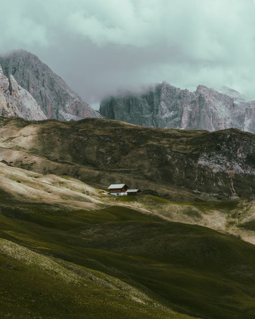 Free A solitary cabin nestled in misty mountains, surrounded by lush green hills. Stock Photo