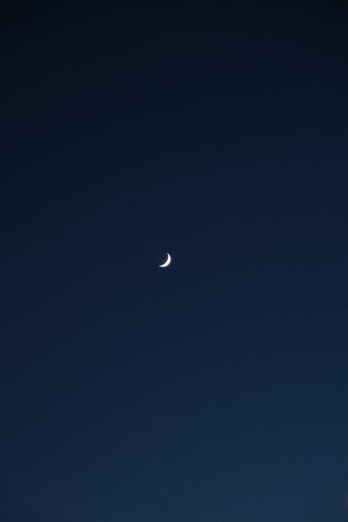 Free A serene crescent moon in a dark evening sky captures the essence of night. Stock Photo