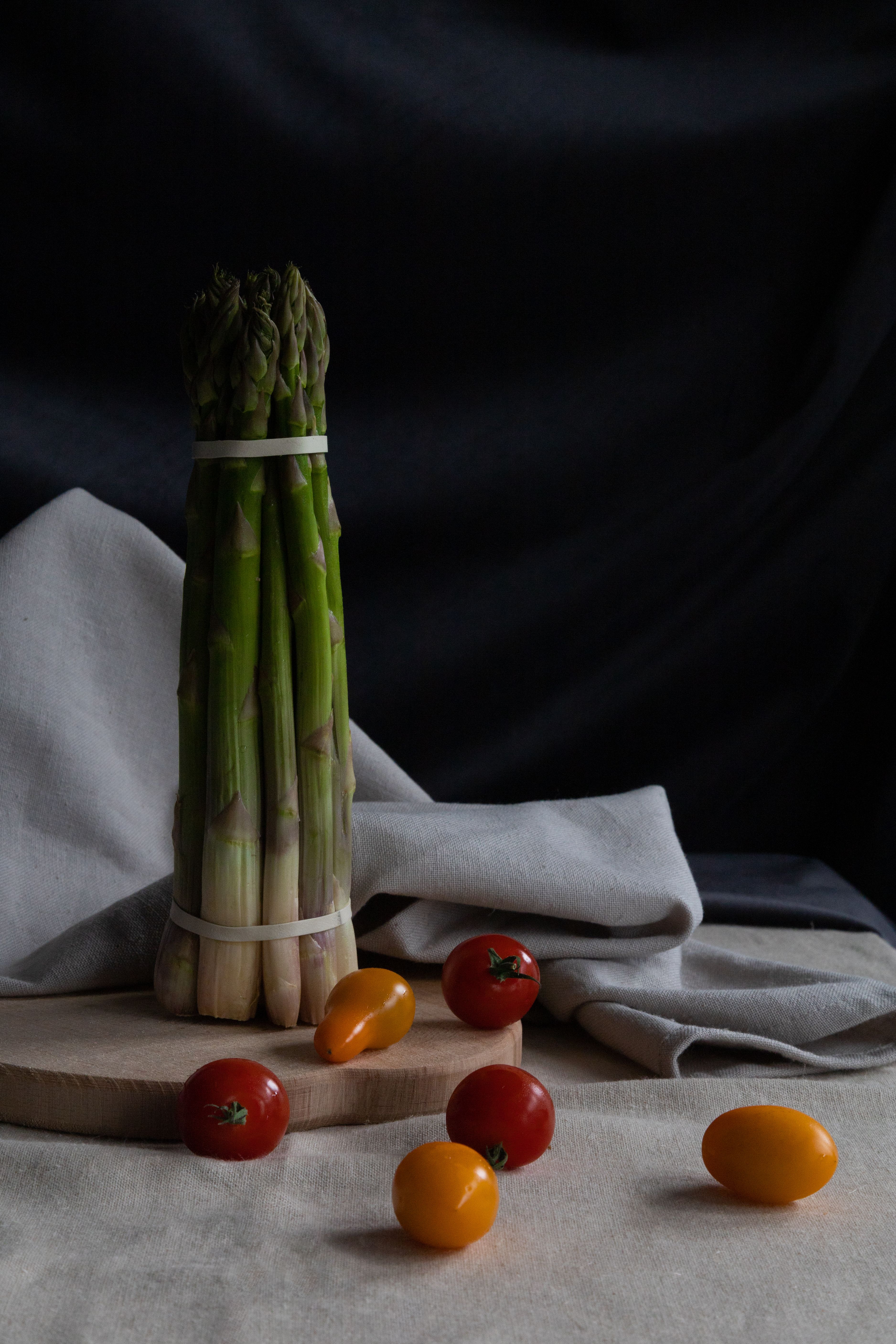 A still life of asparagus and cherry tomatoes on a fabric backdrop, showcasing fresh ingredients for healthy cooking.
