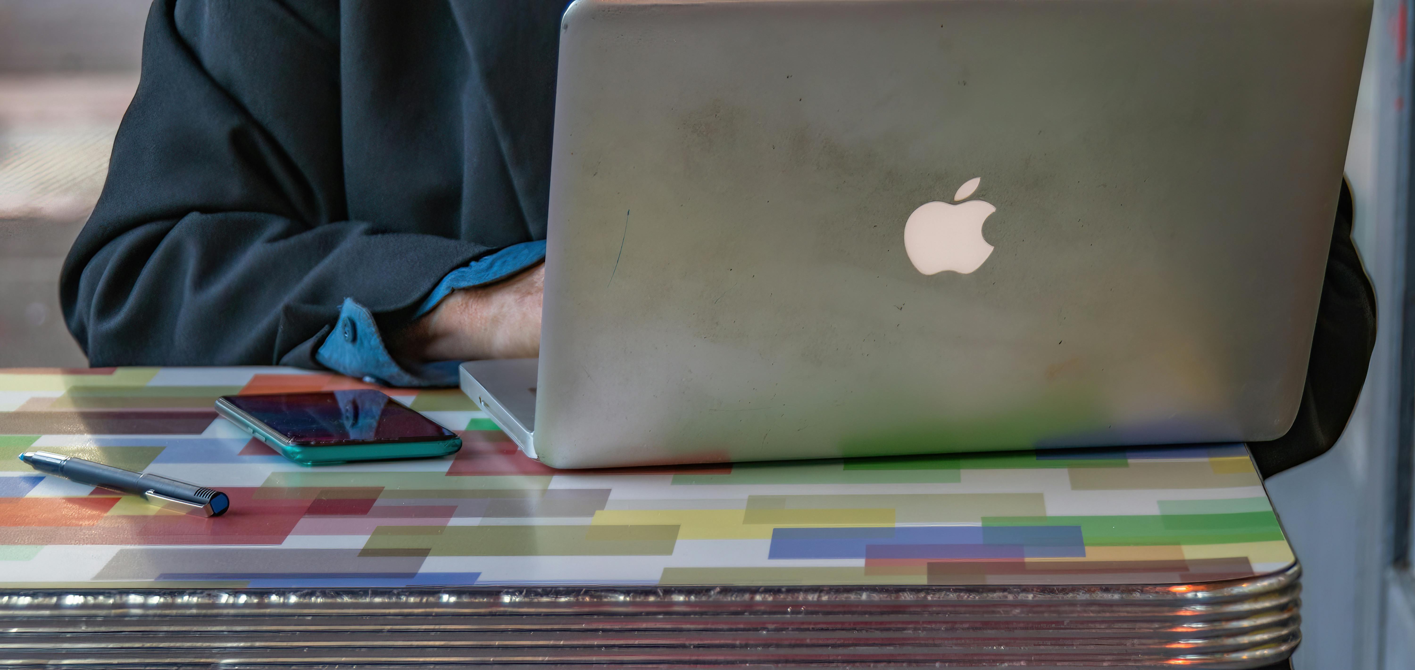 Close-up of a person using a laptop and smartphone on a colorful patterned table indoors.