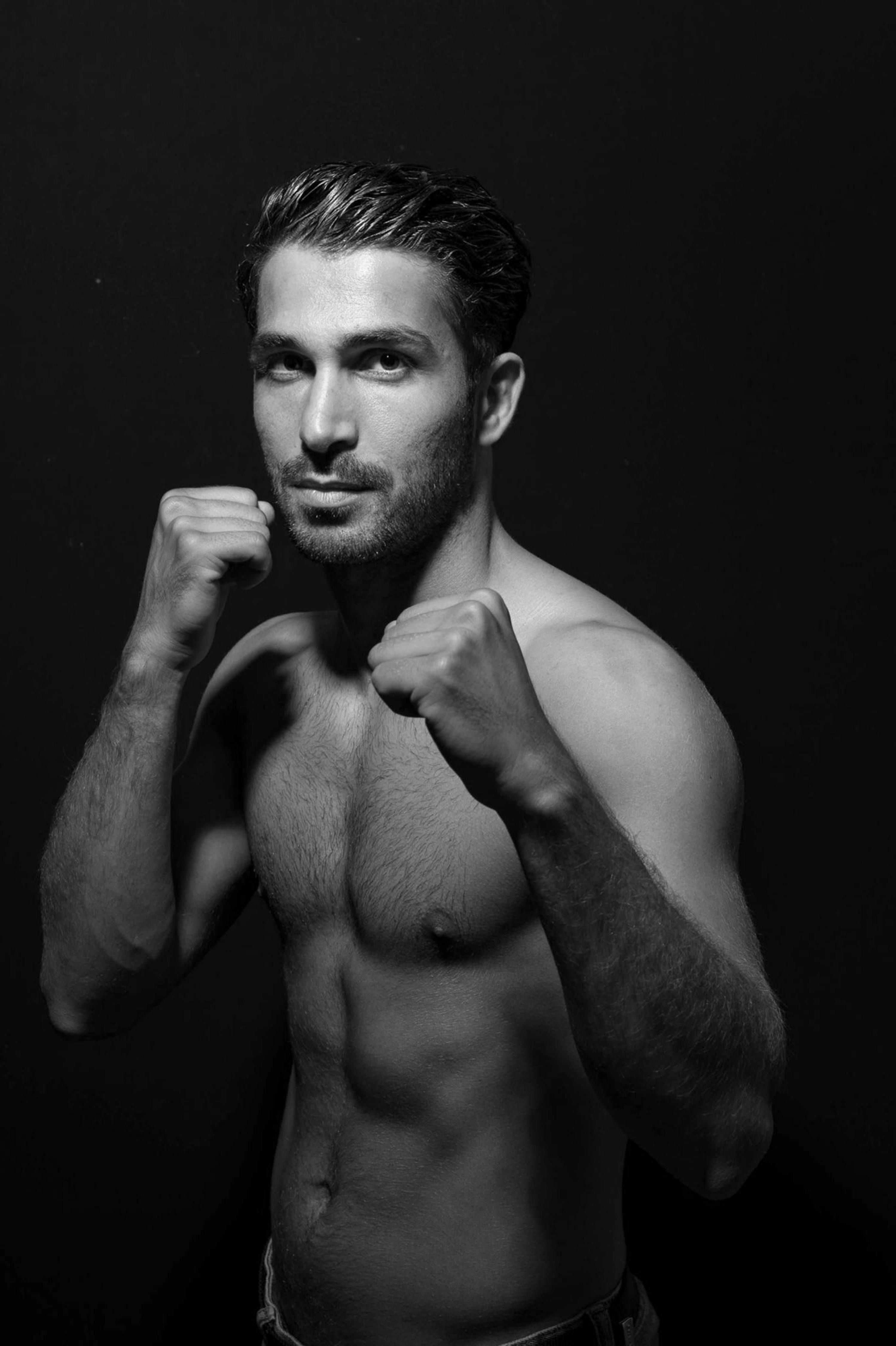 Fotomural Retrato en escala de grises de un hombre sin camiseta en una postura de boxeo, mostrando fuerza y concentración.