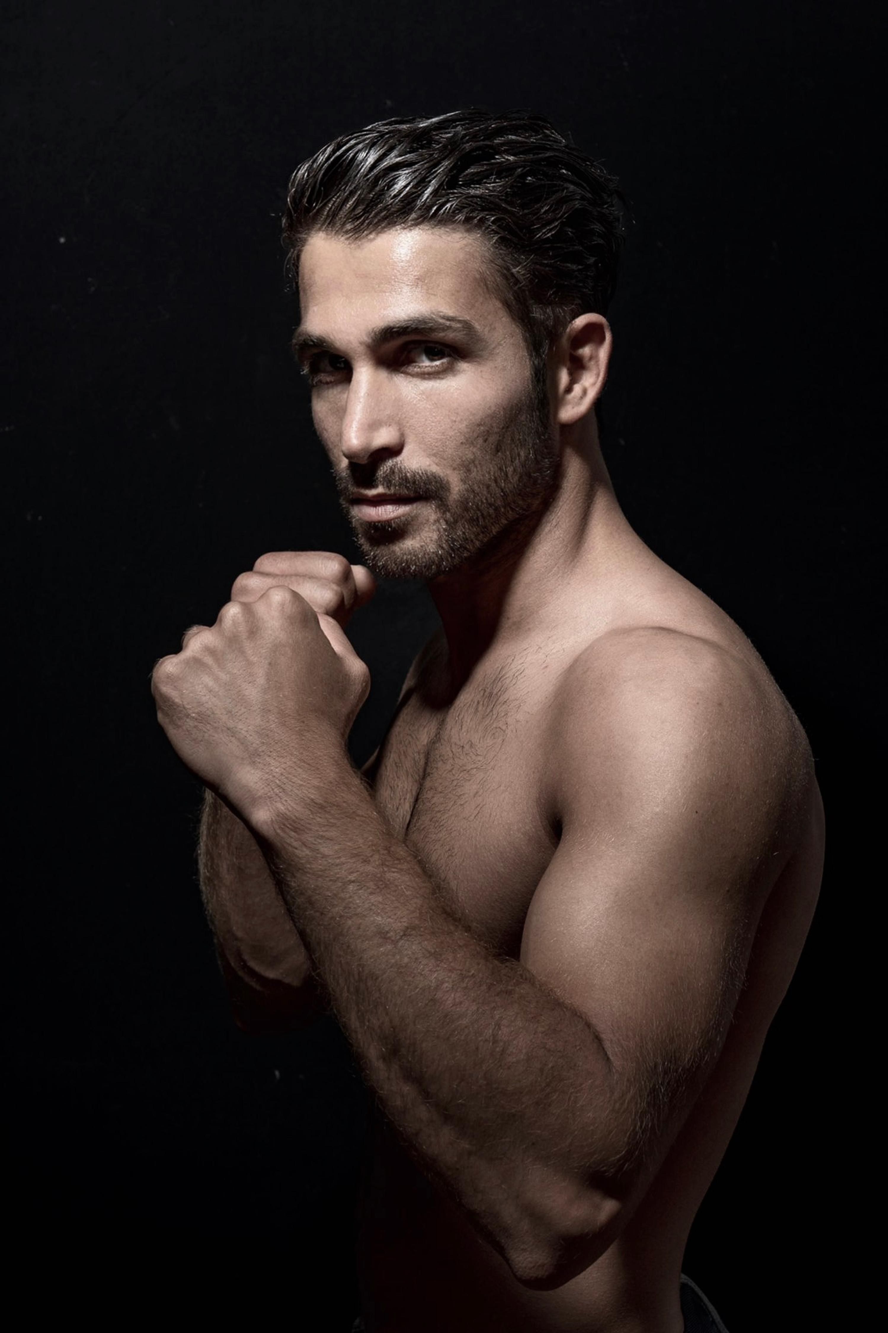 Profile portrait of a shirtless, muscular man in fighting stance with intense expression.