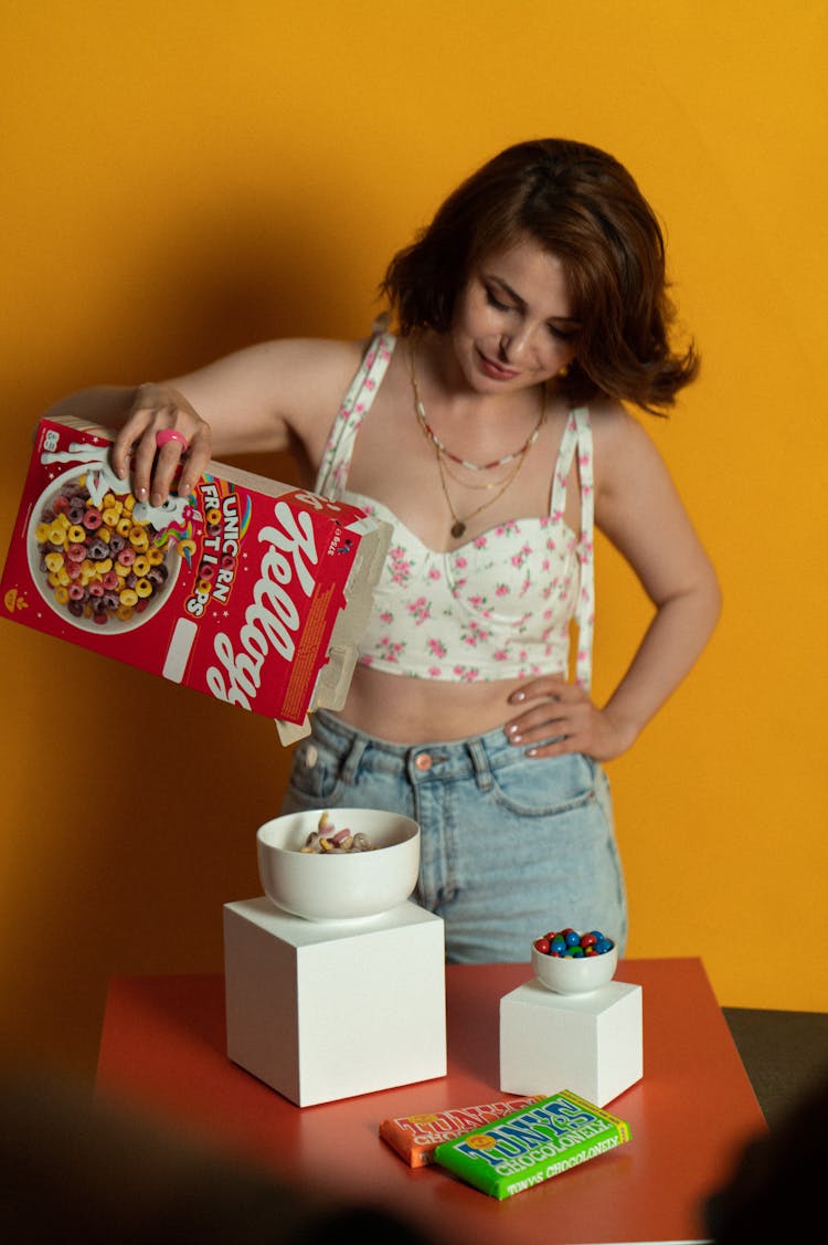 A Woman In A Floral Bralette Pouring Cereal In A Bowl