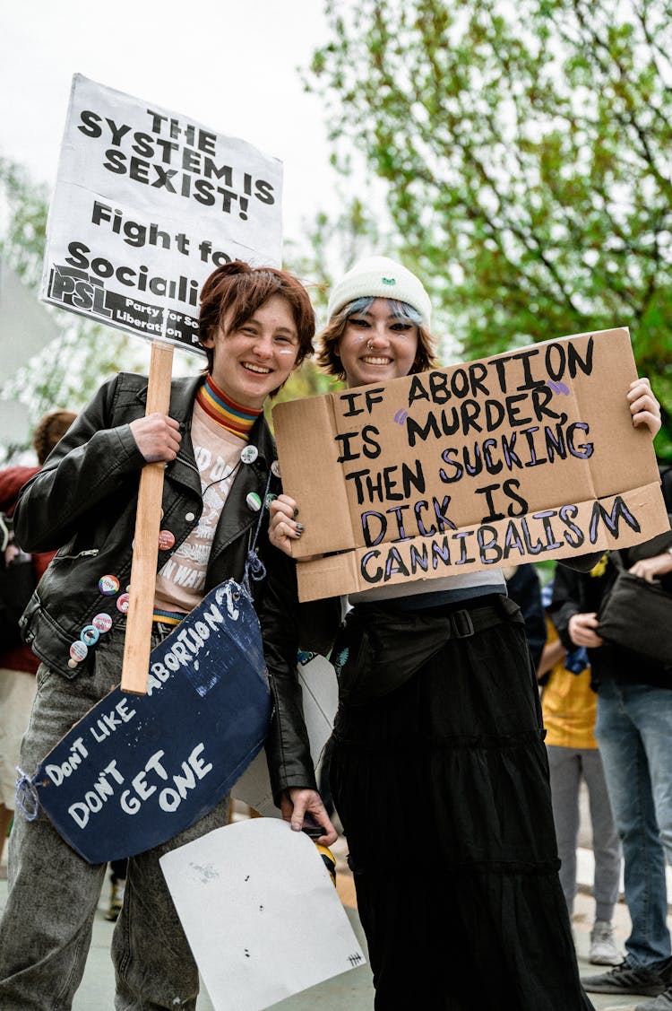 Photo Of Two Smiling People Standing While Holding Banners About Abortion