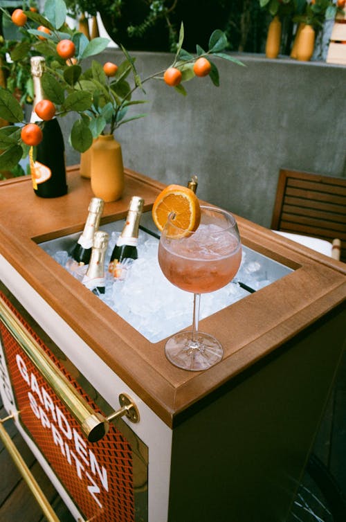 A Cocktail Standing on the Edge of a Counter and Champagne Bottles Cooling in Ice 
