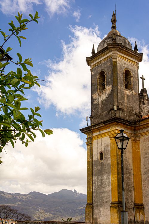 Free Beautiful church tower in Ouro Preto, Brazil, with scenic mountain backdrop under a bright sky. Stock Photo