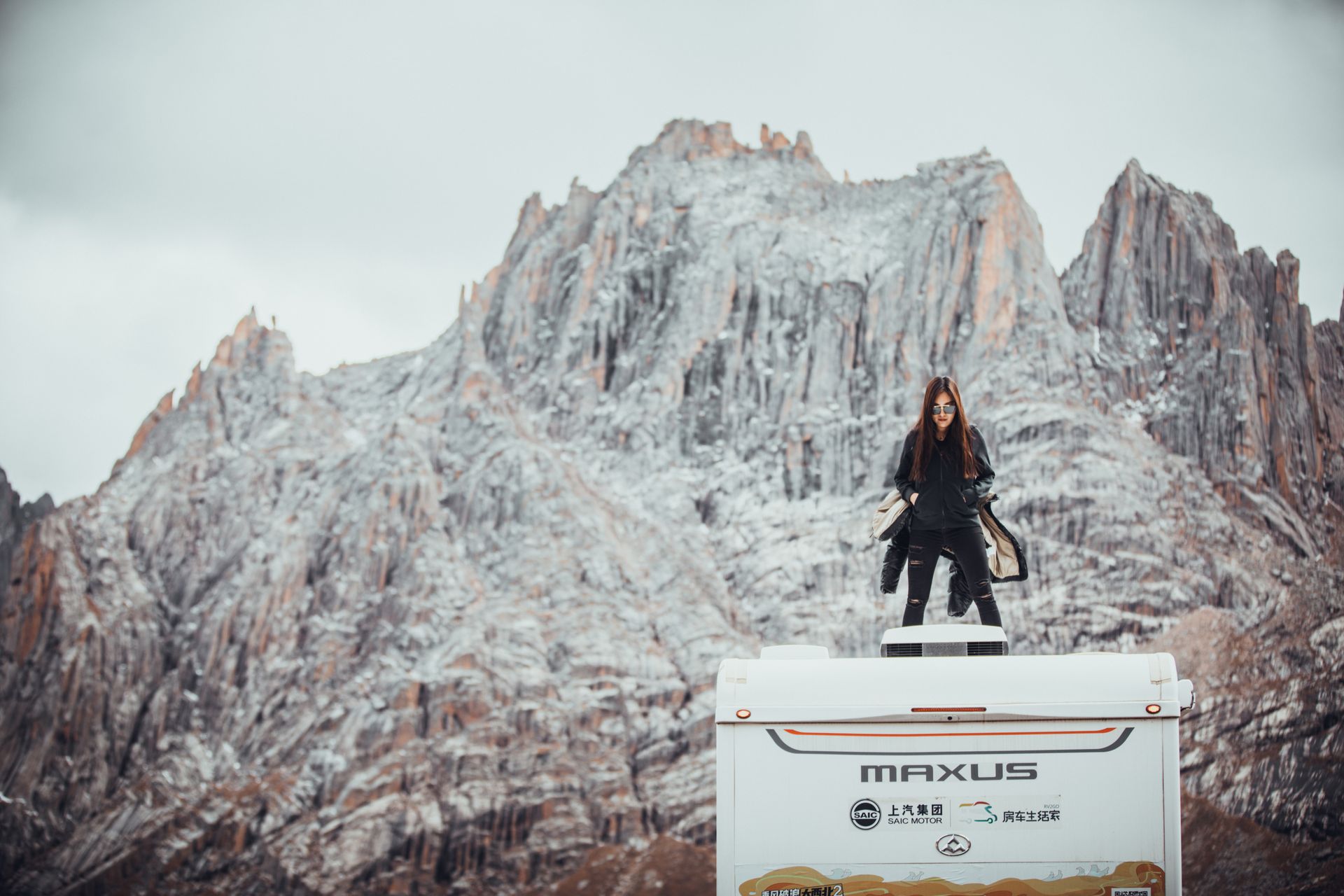 Woman in Black Jacket Standing over a Van Roof