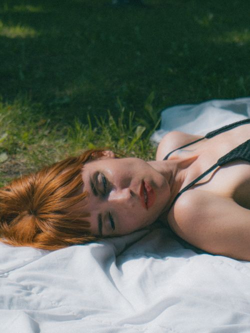 Free Close-up of a redhead woman relaxing on a picnic blanket outdoors in sunny weather. Stock Photo