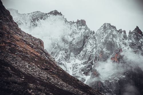 Free Breathtaking snow-covered mountains shrouded in misty fog create a dramatic landscape. Stock Photo