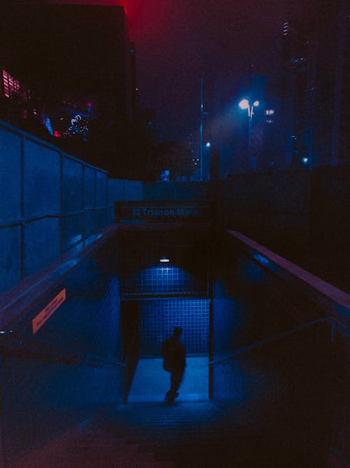 Man Walking Down a Subway Entrance at Night 