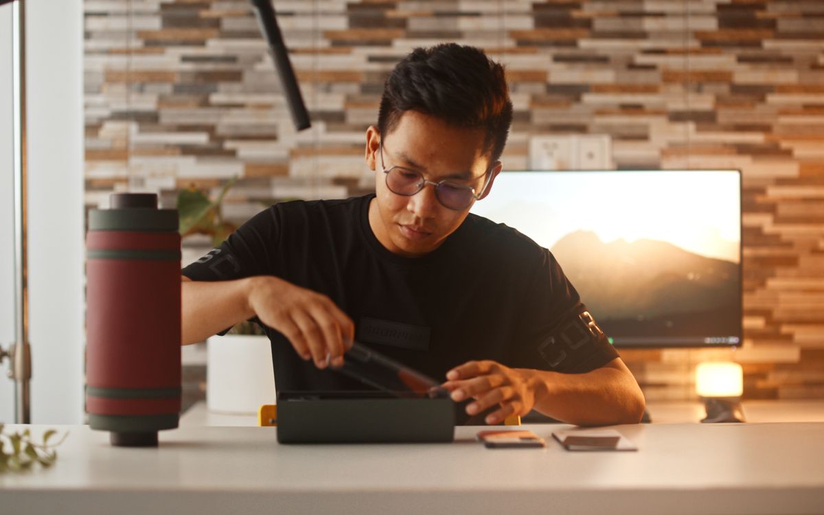 A young man unboxes a smartphone, showcasing modern technology in a cozy indoor setting.