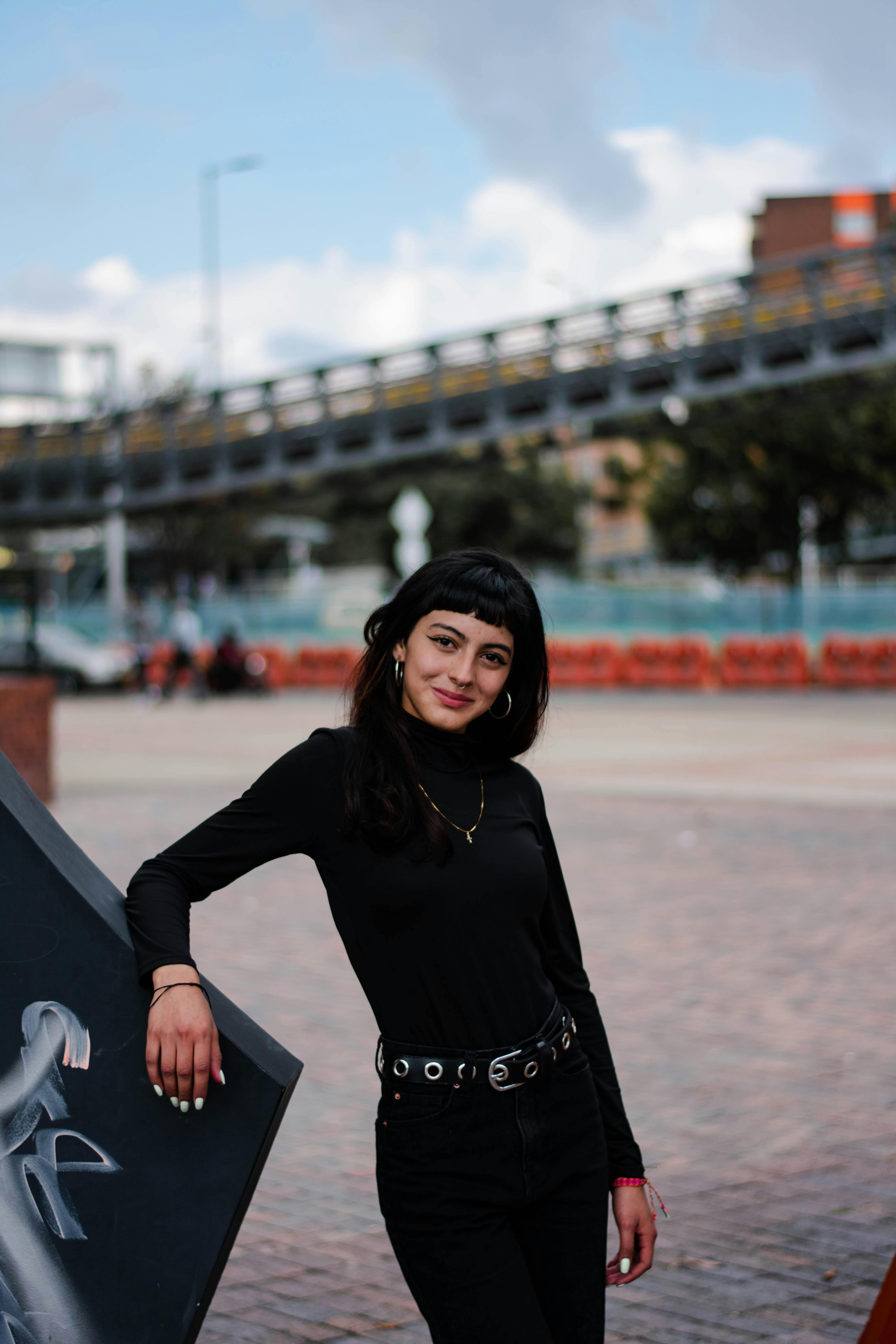 a smiling woman in black long sleeve shirt and black pants