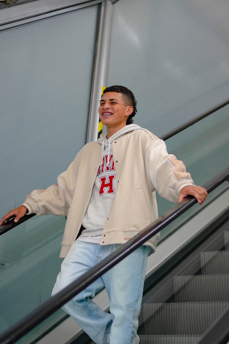 Man In Beige Jacket Going Down On Escalator