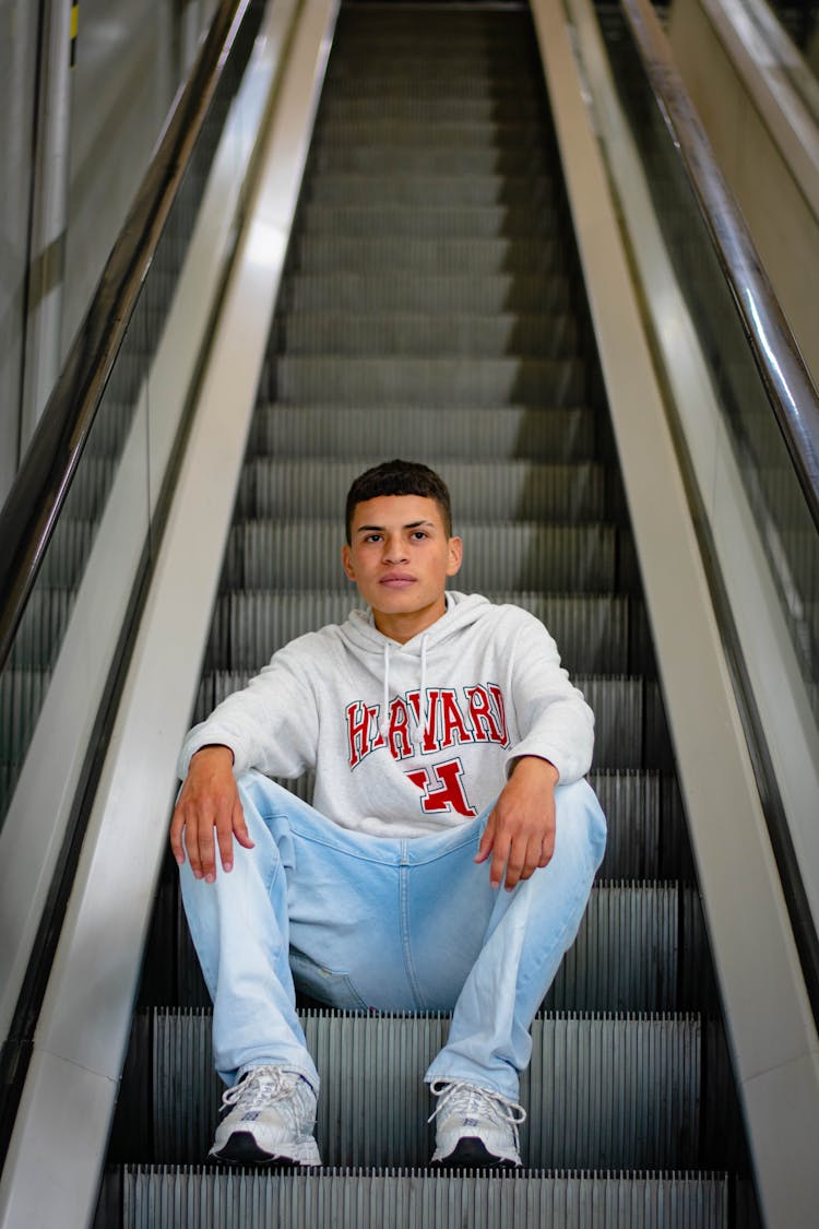 A Young Man I Casual Wear Sitting On Escalator Step