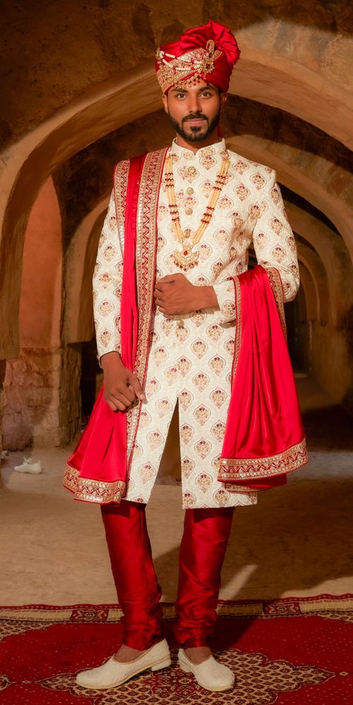 Free Indian man posing in traditional wedding attire with ornate details and vibrant colors. Stock Photo