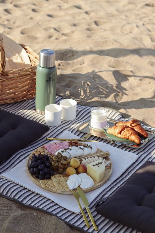 Free Delightful beach picnic setup featuring a gourmet snack tray, croissants, and a relaxing atmosphere. Stock Photo