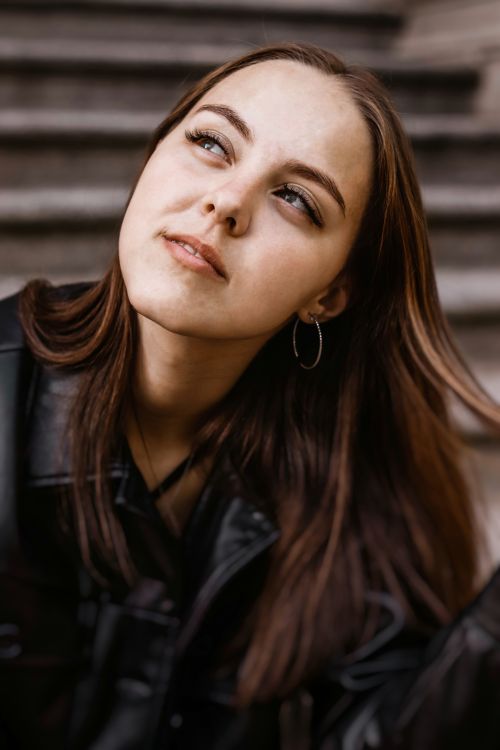 Free Close-up portrait of a Caucasian woman in a black leather jacket, looking thoughtful on steps. Stock Photo