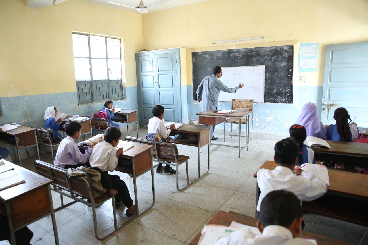 Elementary classroom with attentive students and teacher at blackboard